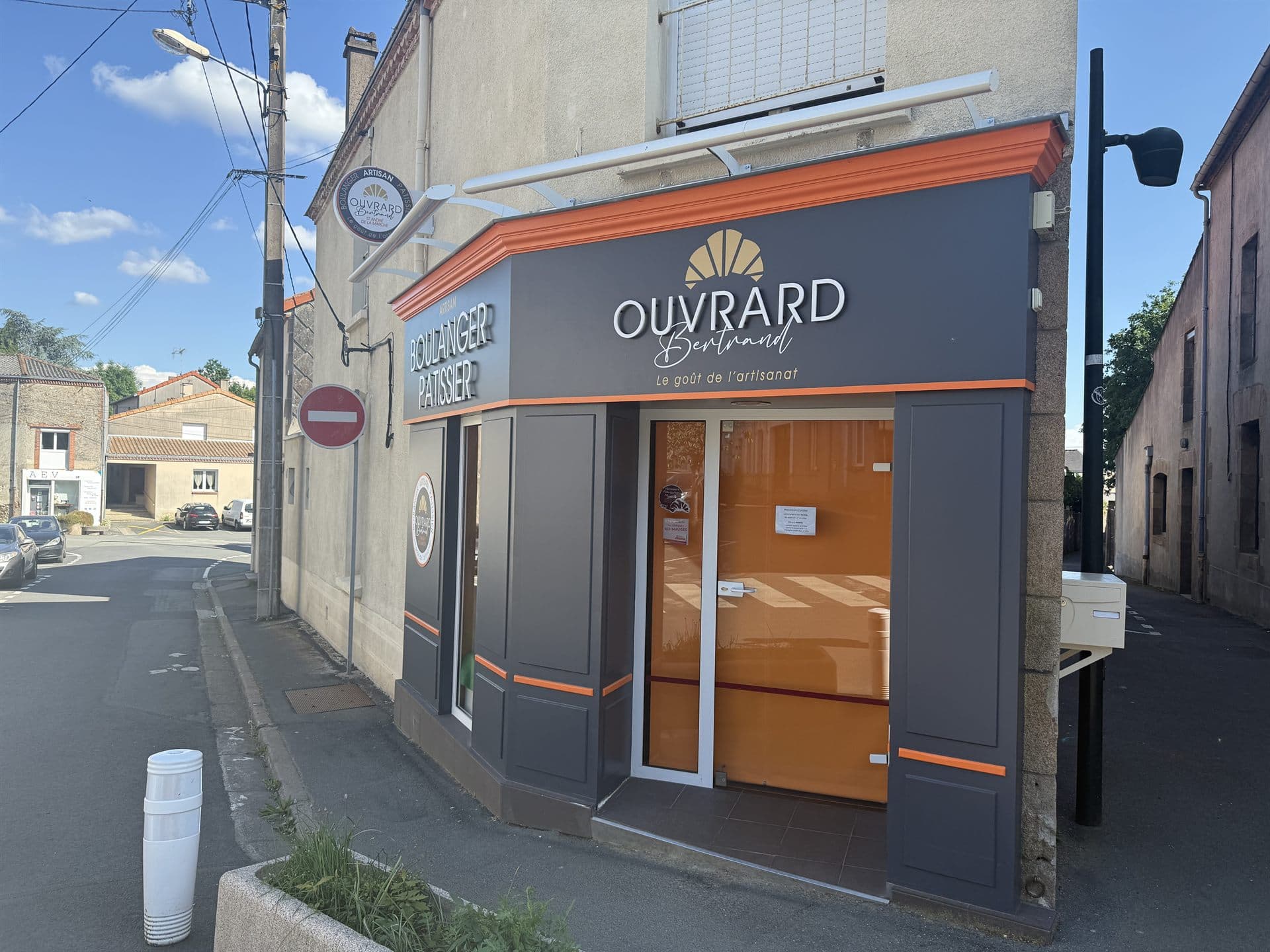 Façade de la Boulangerie Ouvrard à Sèvremoine, peinte en gris anthracite avec liserés orange et l'enseigne « ARTISAN BOULANGER PATISSIER »
